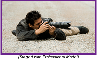 Photographer laying on the ground shooting a picture with a long lens camera (Staged with Professional Model).